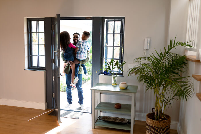 Man holding two children at the door, representing signs you grew up sheltered in a bright home setting.