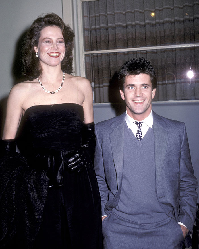 Tall female star in a black dress standing next to a shorter male star in a gray suit, highlighting super tall celebrities over 6 feet.