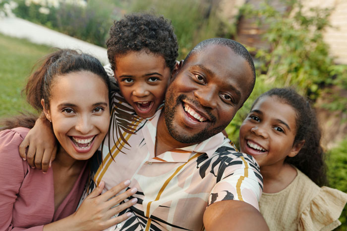 Happy family smiling outdoors with man running after kids and woman lounging on the couch in casual setting