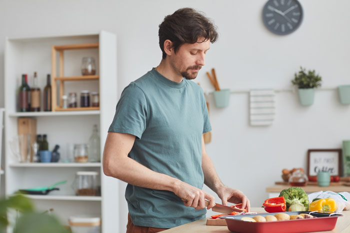 Man preparing vegetables in kitchen, reflecting on SIL shares stats about men leaving sick wives and infertility challenges. - 5