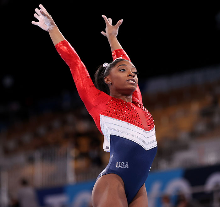 Simone Biles performing gymnastics floor routine in a red and blue USA leotard sparking plastic surgery speculation.