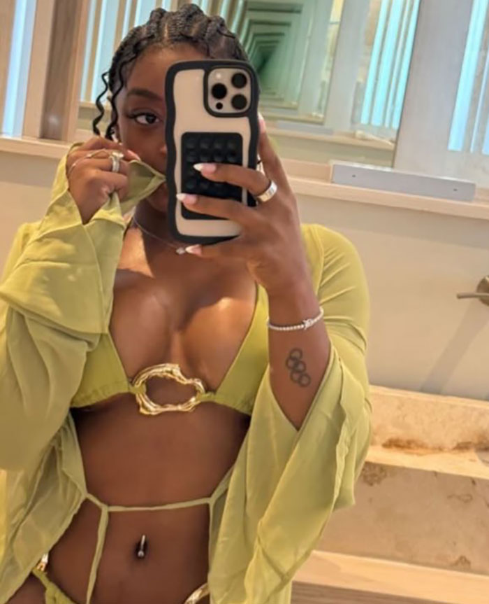 Simone Biles takes a mirror selfie showcasing her new look, sparking plastic surgery and retirement rumors on vacation.