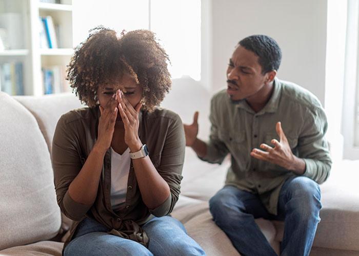 Woman upset and covering face while man angrily gestures during tense moment illustrating single women avoiding men like plague