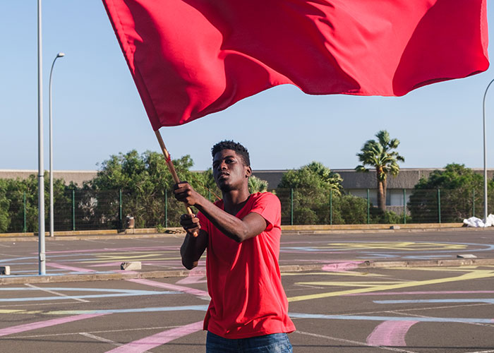 Man waving a large red flag outdoors, symbolizing warnings related to why single women avoid men like the plague.