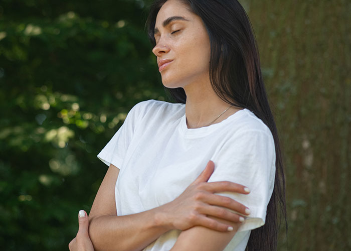 Young single woman standing outdoors with eyes closed, reflecting on why single women avoid men like the plague.