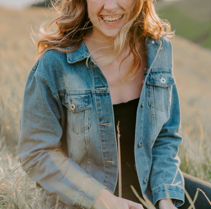 Young woman smiling outdoors in denim jacket, representing behaviors linked to toxic femininity traits and attitude. - 28