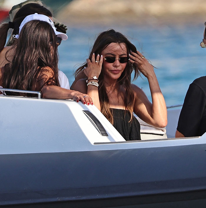 Sof&iacute;a Vergara enjoying a summer romance boat ride, wearing sunglasses and black dress with friends by the sea.