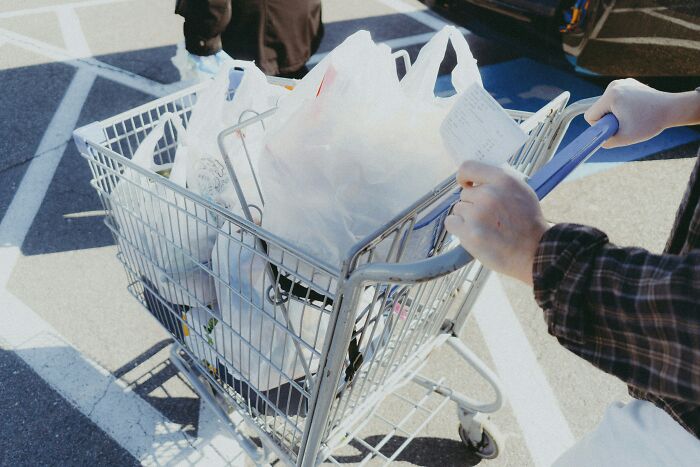 Person pushing a shopping cart filled with groceries outside a store, illustrating people share things improved life concept. - 27