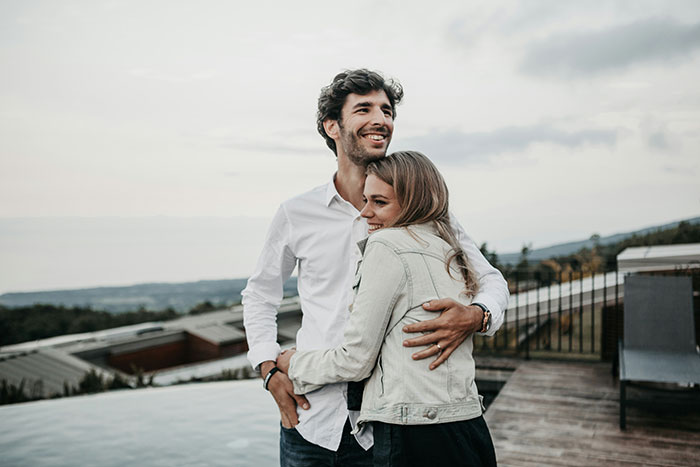 Young woman and man smiling and hugging outdoors, illustrating a woman thinking she got away with being a gold digger. - 61