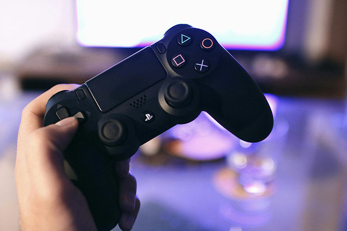 Hand holding a black game controller with blurred background, symbolizing a gold digger getting a harsh lesson soon. - 37