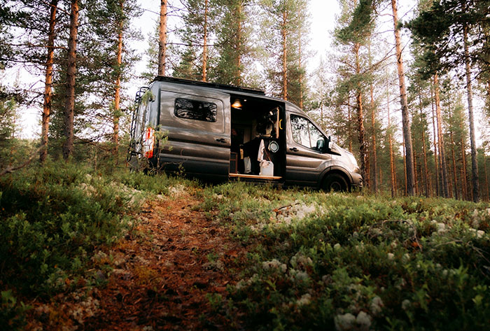 Van parked in a forest setting, representing childhood memories and stories from people's early life experiences.