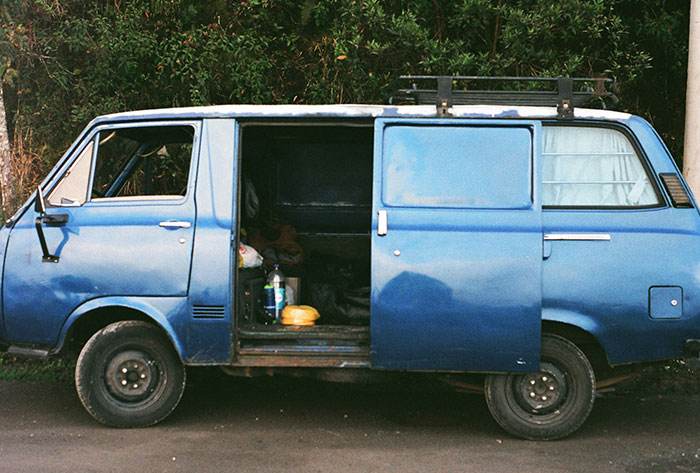 Blue vintage van with open sliding door, symbolizing childhood memories and stories that were really messed up.