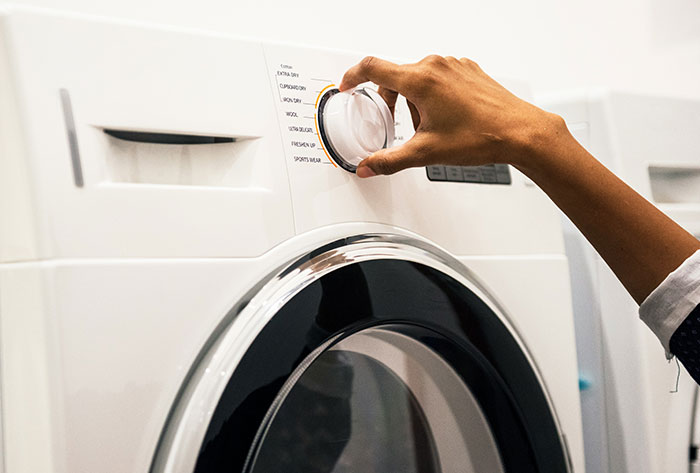 Person adjusting settings on a washing machine, illustrating childhood stories that seem normal but were actually messed up