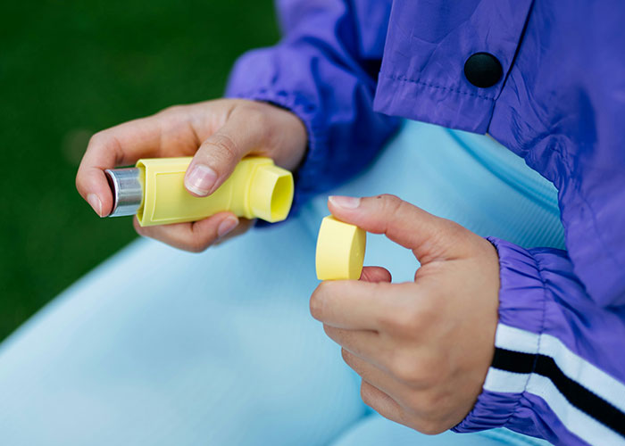 Close-up of a child holding a yellow inhaler, wearing a purple jacket and light blue pants, symbolizing school punishment concerns. - 3