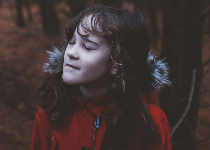 Young girl in a red jacket outdoors, reflecting on memories of being punished for things at school. - 32