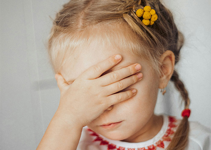 Young girl covering her face with hand, symbolizing upset feelings about school punishments and discipline issues. - 28
