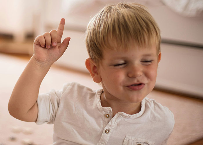 Young child at home raising finger as if answering a question about things punished at school. - 33