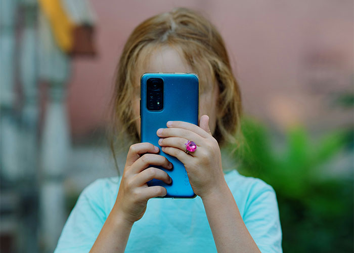 Child holding a smartphone outdoors, illustrating people still upset about things they were punished for at school. - 35