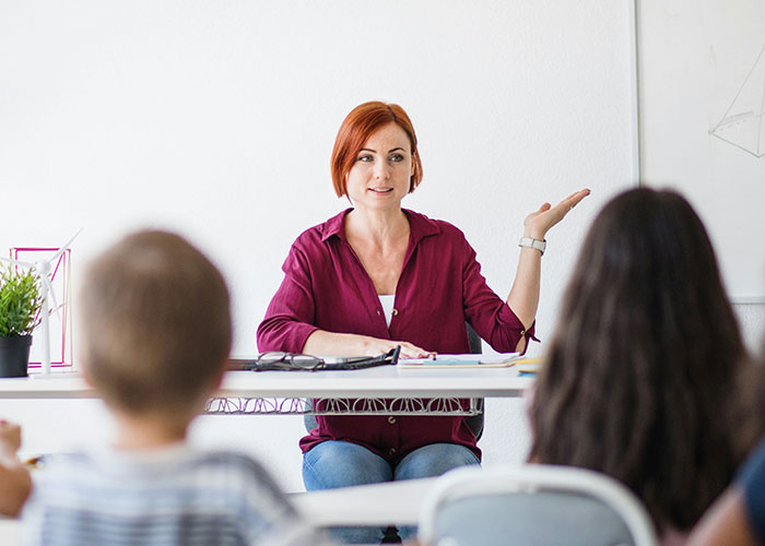 Female teacher in classroom explaining to students about school rules and punishments for various behaviors. - 9