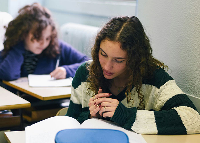 Student focused on reading a book in a classroom, representing school punishments people are still upset about. - 7