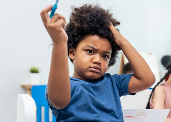 Young student looking frustrated while holding a pen, showing emotions related to being punished at school. - 19