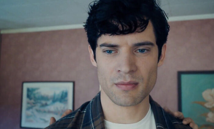 Young man with dark hair and blue eyes looking down in a room, representing woke Superman reboot early reviews and flop criticism.