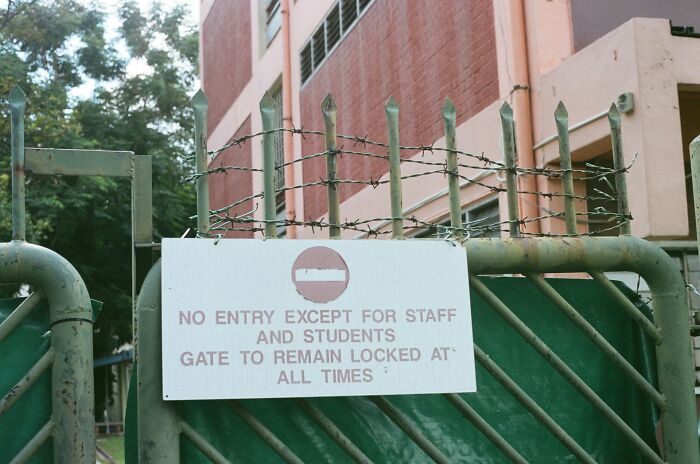 Locked gate with a sign restricting entry to staff and students, illustrating the importance of communicating calmly in rules.