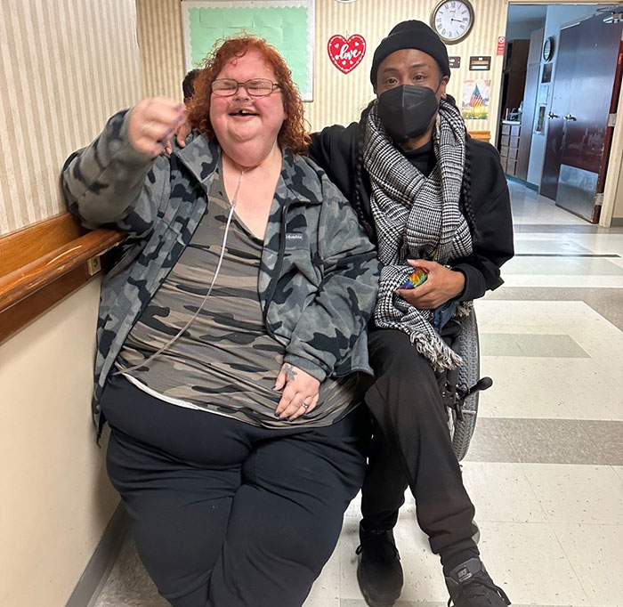 Tammy Slaton from 1000-Lb. Sisters sitting next to a friend, both smiling in a hallway setting after surgery. - 3