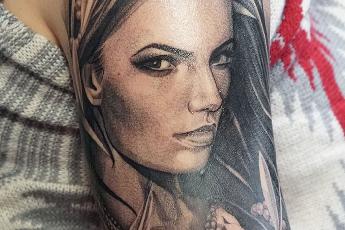 Realistic tattoo portrait on skin showing detailed shading and facial features by tattoo artists on moral grounds.