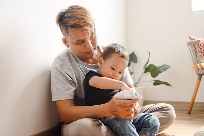17-year-old babysitting sister’s kids, showing care and attention while sitting on the floor playing with a toy. - 1