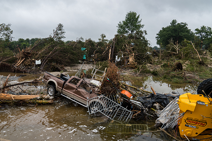 Flooded area in Texas showing debris and a damaged truck after floods affecting family of Travis Kelce's boss