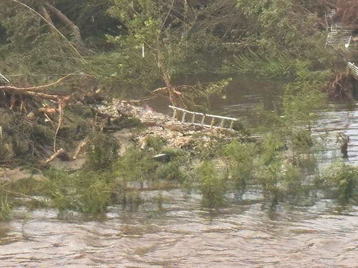 Flooded Texas landscape with debris and a damaged ladder, representing sisters who lost their lives in Texas floods.