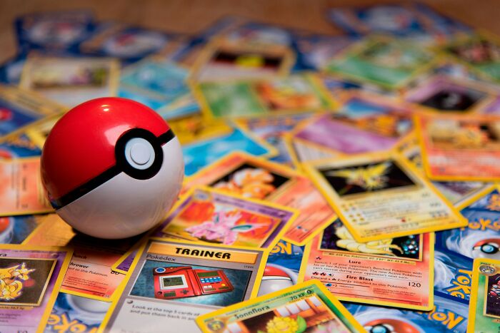 Pokémon cards and a Poké Ball displayed as high-value collectible items sold for millions in auctions.