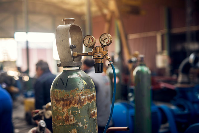 Rusty gas cylinder with pressure gauges in an industrial setting showing seemingly innocent things that are deadly hazards.