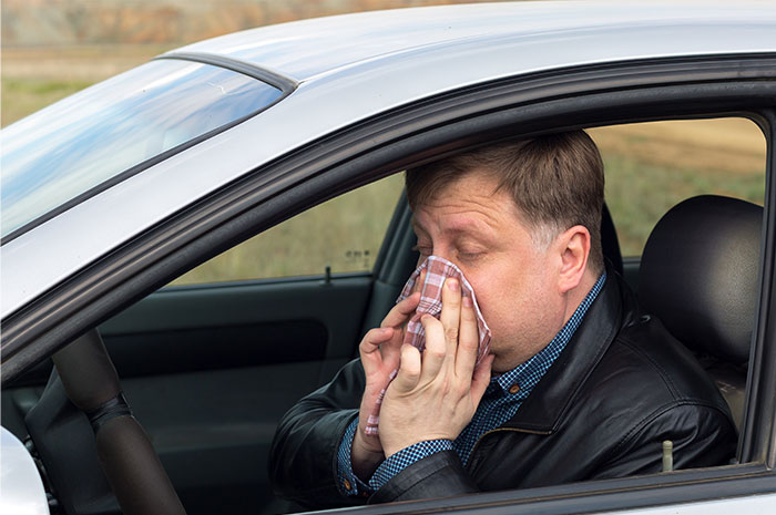 Man inside car holding a tissue to his nose, illustrating seemingly innocent things that are deadly risks.