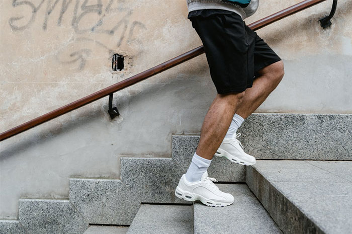 Person wearing white sneakers and black shorts walking up concrete stairs, illustrating seemingly innocent things that are deadly.