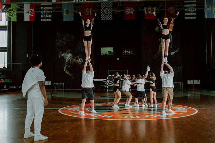 Cheerleaders practicing stunts in a gym, highlighting seemingly innocent things that are deadly risks in sports activities.