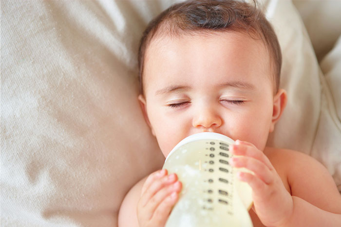 Baby peacefully drinking milk from a bottle, illustrating seemingly innocent things that can be deadly risks for infants.