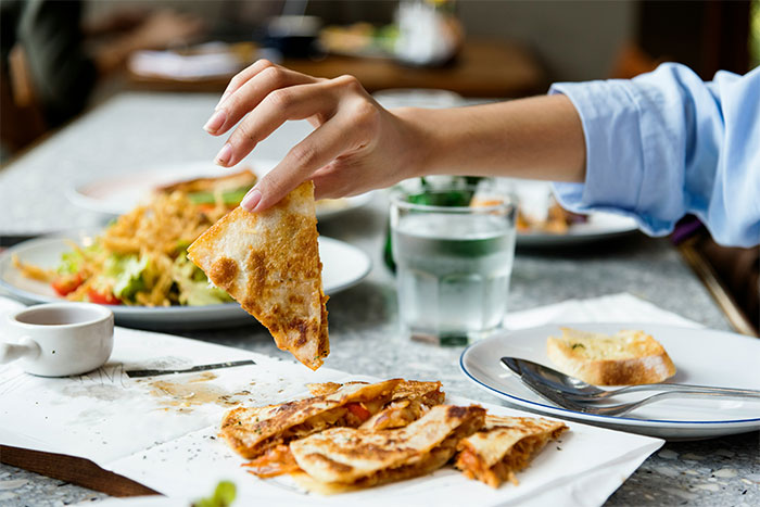 Hand picking a slice of pizza from plate, illustrating seemingly innocent things that are deadly in everyday food choices.