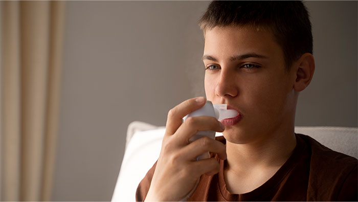 Teen using an inhaler for respiratory issues, highlighting one of the seemingly innocent things that are deadly risks to health.