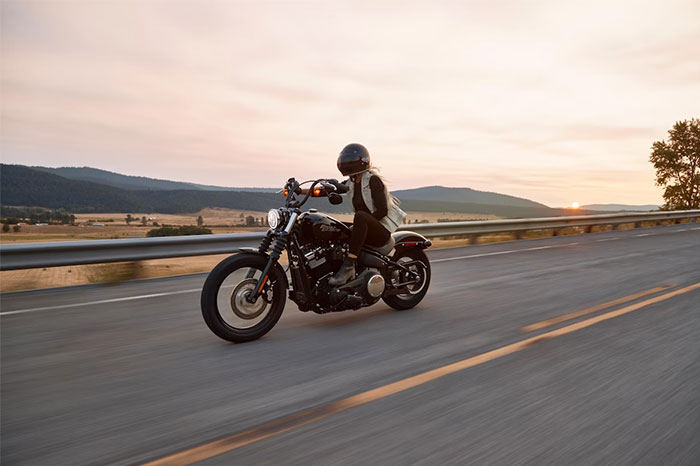 Woman riding a motorcycle at sunset on an open road, illustrating one of the seemingly innocent things that are deadly.