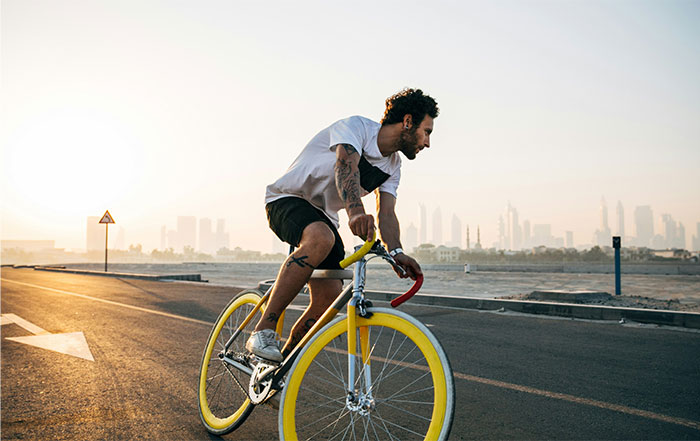 Man riding a yellow road bike on an empty street at sunset, illustrating seemingly innocent things that are deadly risks.