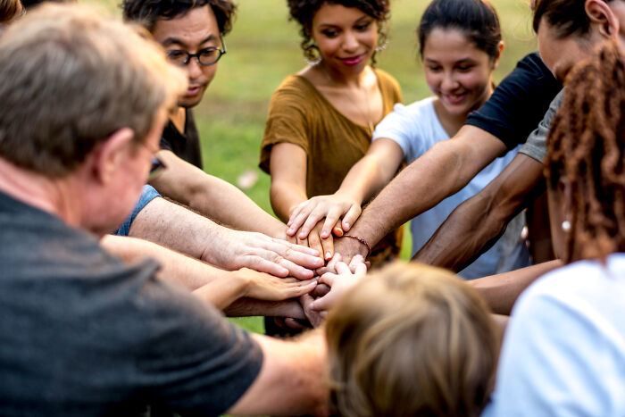 A diverse group of people stacking hands together, symbolizing trust and patience from the good old days.