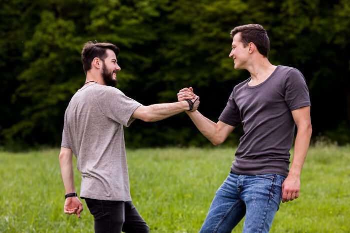 Two young men outdoors shaking hands, symbolizing trust and patience from the good old days slowly disappearing.