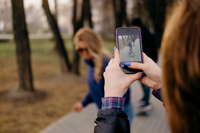 Person capturing a photo of a child on a skateboard outdoors, reflecting things from the good old days slowly disappearing.