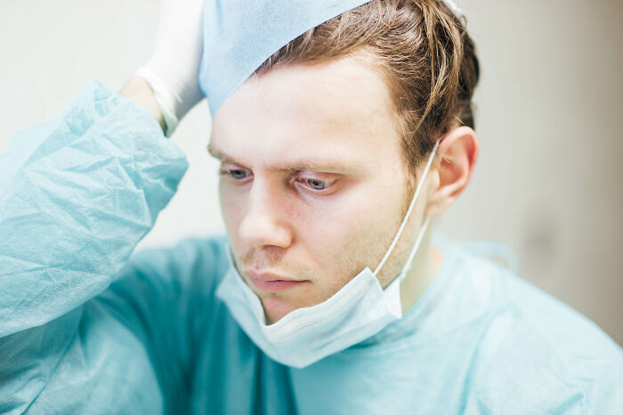Medical examiner in protective clothing and mask, preparing to deal with dead bodies in a clinical environment.