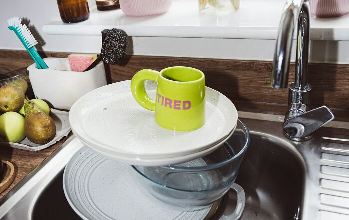 Dirty dishes piled high in kitchen sink, illustrating awful roommate habits and messy shared living spaces.