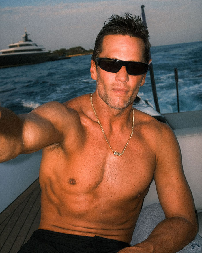 Tom Brady shirtless on a boat wearing sunglasses, highlighting his summer romance and playful vibe with Sofia Vergara.