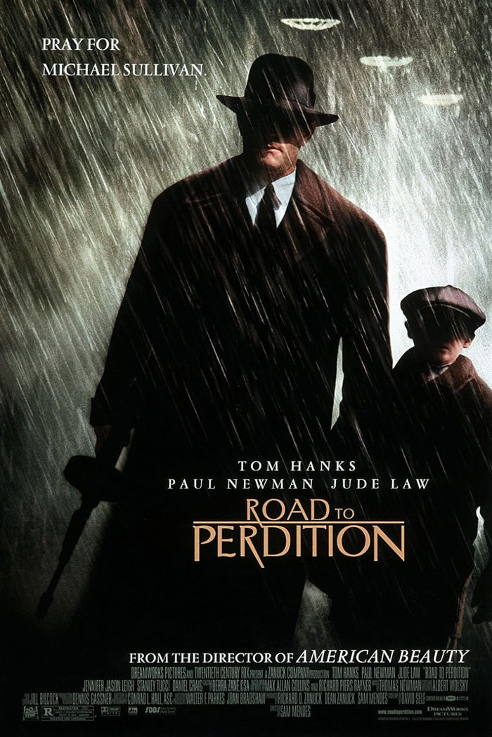 Tom Hanks in Road to Perdition poster, standing in rain with a child, highlighting an underrated Tom Hanks movie.