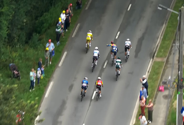Tour De France fans standing on graves along roadside to get a better view of cyclists during the race.